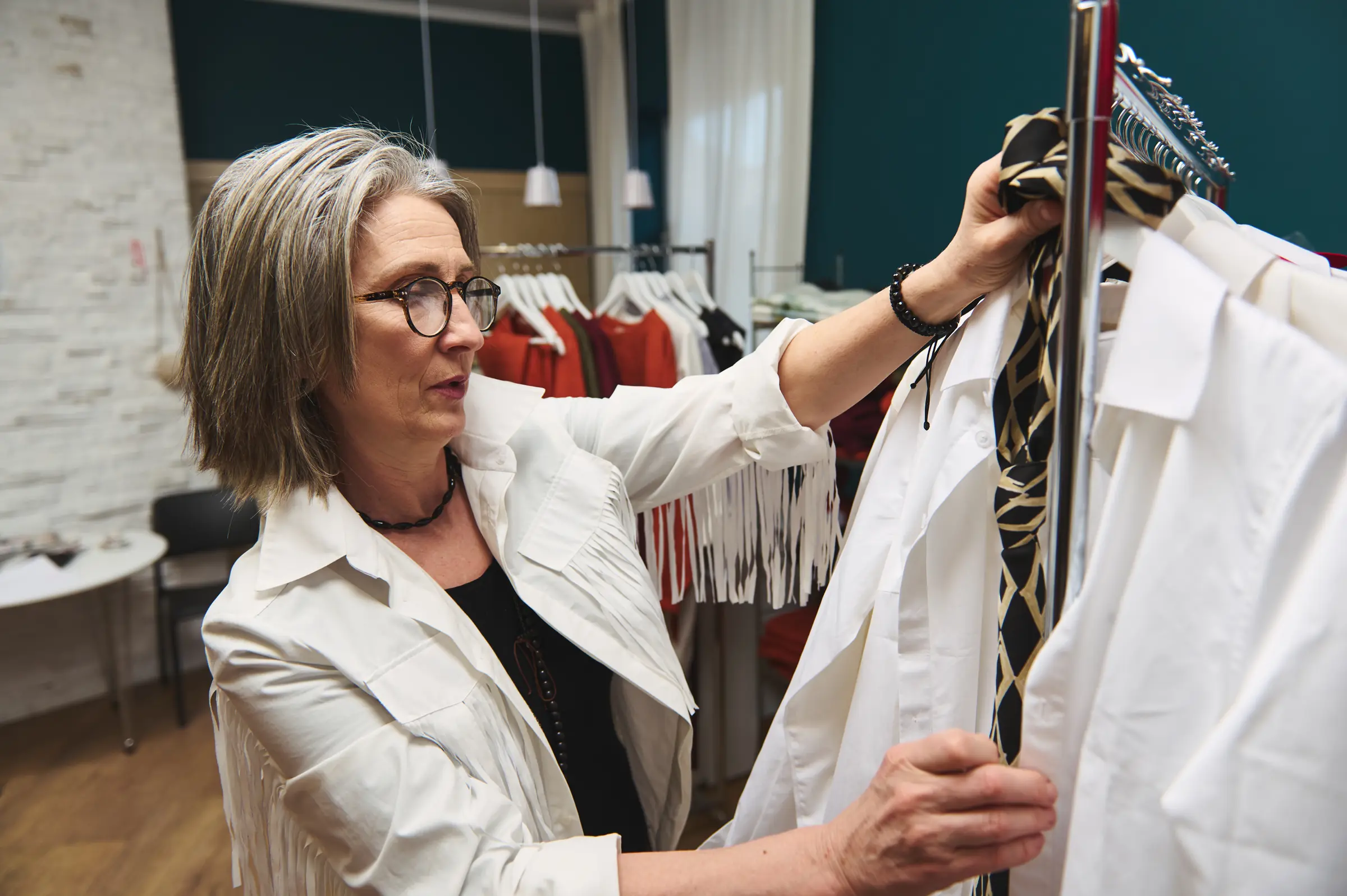 A fashion designer adjusting garments on a rail in her studio